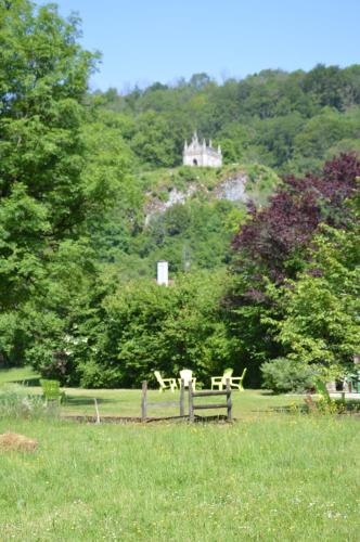 a park with picnic tables and a castle in the background at Moulin de la Cuse - Chambre La Cuse in Cusance