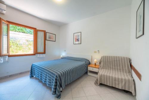 um quarto com uma cama, uma janela e uma cadeira em Casa Luppoli em Portoferraio