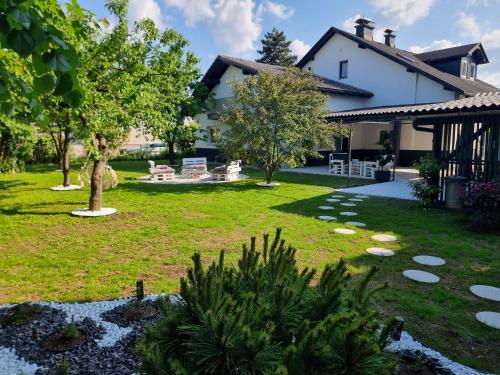 Lora & Lana Resort في ليوبليانا: ساحة بها منزل وحديقة بها أشجار