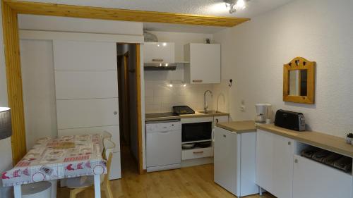 une cuisine avec des armoires blanches et une table à l'intérieur dans l'établissement Résidence Alpinéa Mottaret, 2 à 4 pers, à Méribel