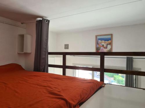 une chambre avec un lit orange et une fenêtre dans l'établissement Studio avec Mezzanine, Plage du Môle à 100m, Proche Commerces et Restaurants, Parking Inclus - FR-1-249-336, au Cap d'Agde
