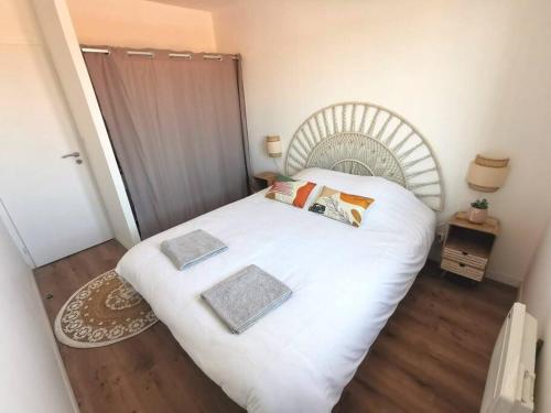 una camera da letto con un letto bianco con due cuscini sopra di Soulac-sur-Mer T4 hypercentre proche mer a Soulac-sur-Mer