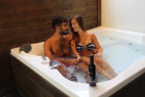 un uomo e una donna seduti in una vasca da bagno con una bottiglia di vino di Rotem's Trail a Netiv HaShayyara