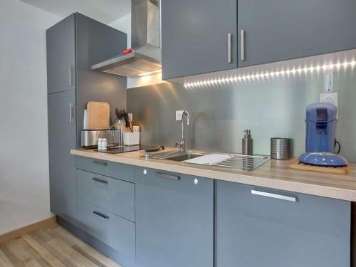 une cuisine avec des armoires bleues et un évier dans l'établissement Beau studio cabine 4 pers, accès WiFi, pied de piste ! - FR-1-400-115, à Eaux-Bonnes
