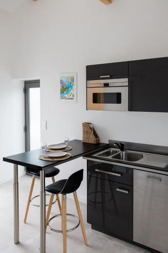 une cuisine avec des comptoirs noirs et une table avec des tabourets dans l'établissement Les Calanques - Clim et Jacuzzi, à Carnoux-en-Provence