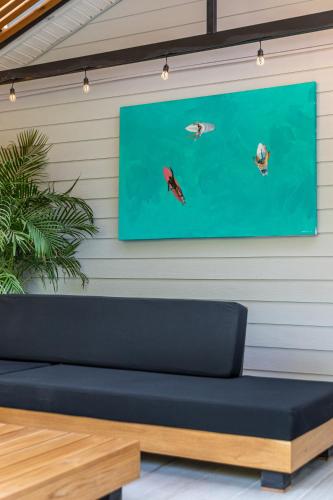 a blue couch against a wall with a painting of fishes at Ventura Santa Teresa in Santa Teresa Beach