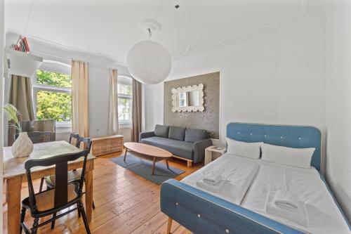 a bedroom with a blue bed and a living room at primeflats - Apartments Schillerpark Berlin-Wedding in Berlin