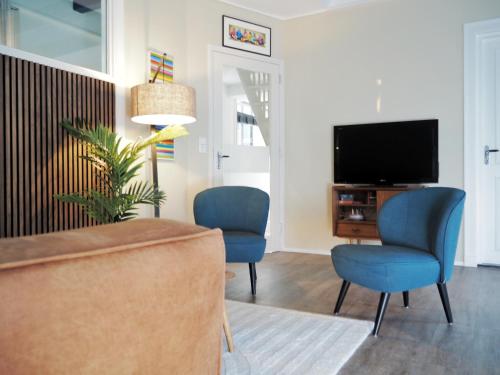 a living room with two blue chairs and a television at ‘t Wirdummer Hof - family-friendly guesthouse in Wirdum