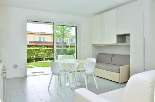 a white living room with a glass table and white chairs at Residence Agorà in Bibione