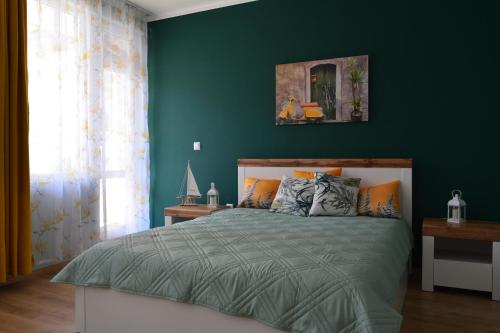 Un dormitorio con una pared verde y una cama en City Center Apartment, en Burgas