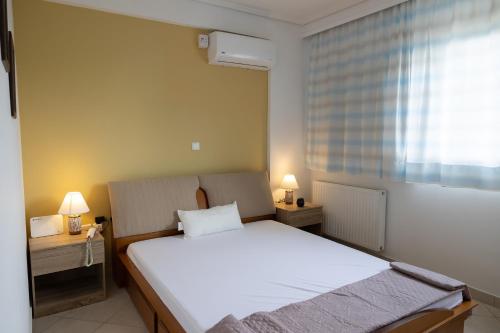 a bedroom with a large white bed and a window at Electra in Saronida