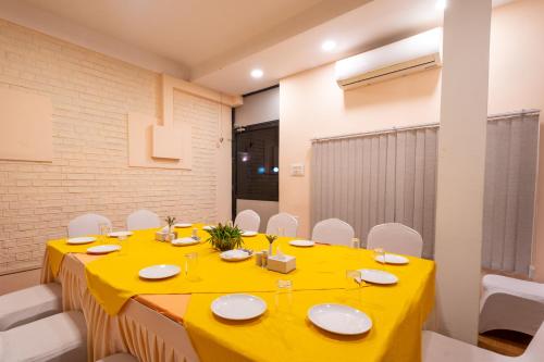 a dining room with a yellow table and white chairs at Dreamland Gold Resort & Hotel in Bhairāhawā