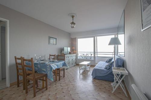 ein Wohnzimmer mit einem Tisch und Stühlen sowie eine Küche in der Unterkunft Les Marinas in Courseulles-sur-Mer