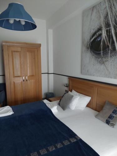 a bedroom with a bed with a blue blanket at Hédervári Lovas Vendégház in Hédervár