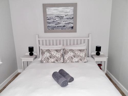a bedroom with a white bed with two pillows on it at Coral Cottage in Struisbaai