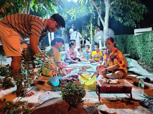 a group of people sitting around a table in a garden at Baan Namthip Homestay Trang บ้านน้าทิพย์ โฮมสเตย์ตรัง in Ban Huai To (1)