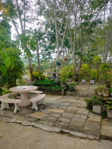 a picnic table and benches in a garden at Baan Namthip Homestay Trang บ้านน้าทิพย์ โฮมสเตย์ตรัง in Ban Huai To (1)