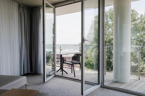 a room with sliding glass doors with a table on a deck at Ultra Marine by Zdrojowa in Kołobrzeg