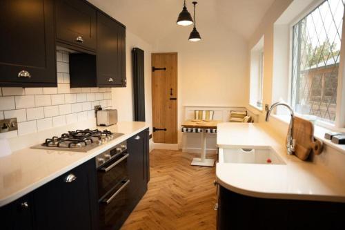 uma cozinha com armários pretos e um forno com placa de fogão em Cosy Village House em Waddington