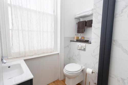 a white bathroom with a toilet and a sink at Number 8 in Canterbury