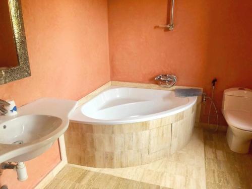 a bathroom with a tub and a sink and a toilet at Villa Apricot - Golf Amelkis in Marrakech