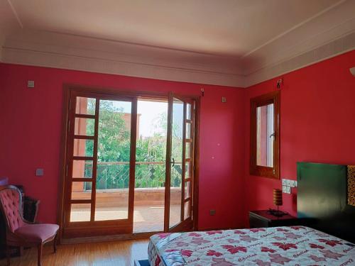 ein rotes Schlafzimmer mit einem Bett und einer Glasschiebetür in der Unterkunft Villa Apricot - Golf Amelkis in Marrakesch