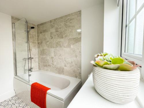 ein Badezimmer mit einer Badewanne und einer Vase mit Blumen darin in der Unterkunft The New Found Lamb in Cleethorpes