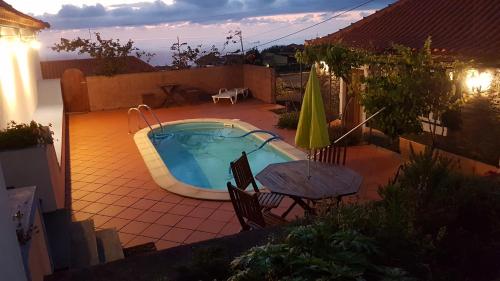 a backyard with a swimming pool and a table and umbrella at Casa Luciana in Ponta do Pargo