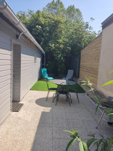 un patio avec une table et des chaises à côté d'un garage dans l'établissement maisonnette cosy bien située, à Dol-de-Bretagne