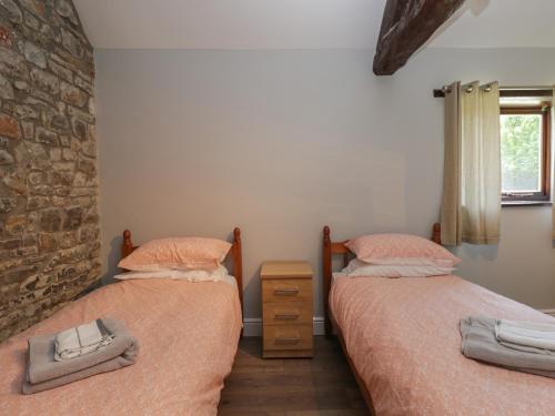 a bedroom with two beds and a brick wall at Swallow Barns in Bristol