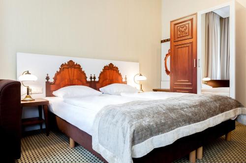 a bedroom with a large bed with a wooden headboard at Jantar Hotel & SPA by Zdrojowa in Kołobrzeg