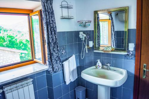 baño de azulejos azules con lavabo y ventana en Villa La Voce Del Vento, en Pastena