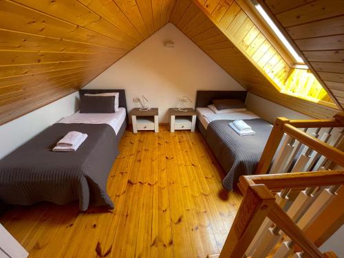 two beds in a attic room with wooden floors at Liliowa 12 in Dębki