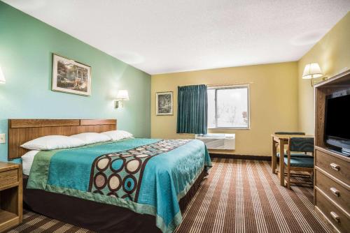 a hotel room with a bed and a flat screen tv at Super 8 by Wyndham Osseo WI in Osseo