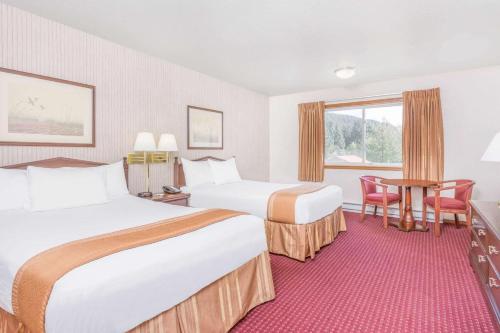 a hotel room with two beds and a table and chairs at Travelodge by Wyndham Juneau in Mendenhaven