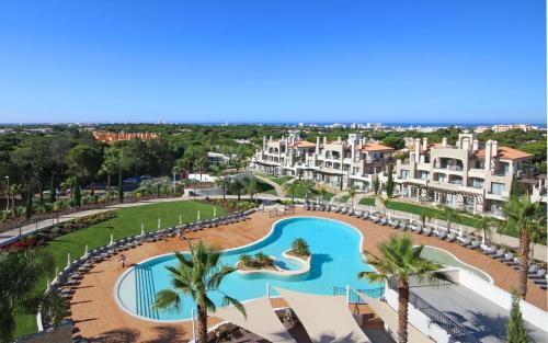 ein Luftblick auf ein Resort mit einem Pool und Palmen in der Unterkunft Vilamoura Pine Hills Luxury Apartment in Quarteira