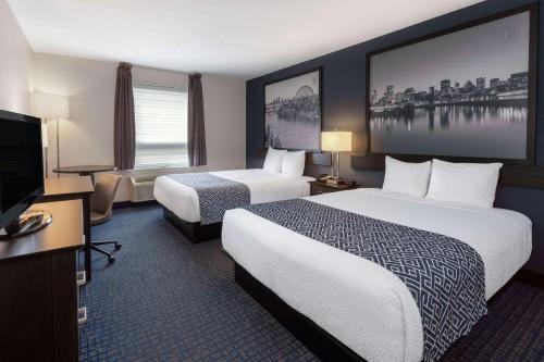 a hotel room with two beds and a flat screen tv at Super 8 by Wyndham Lachenaie/Terrebonne in Terrebonne