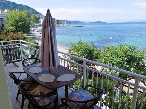 a table and chairs with an umbrella on a balcony at Vassia's Beach Houses in Benitses