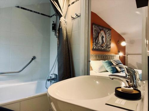 La salle de bains est pourvue d'un lavabo et d'une baignoire. dans l'établissement Hotel Le Patio - Deauville, à Deauville