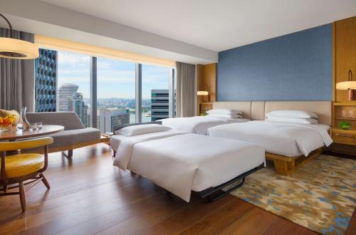 a hotel room with four beds and a large window at Andaz Singapore, By Hyatt in Singapore