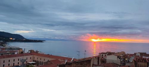 a sunset over the ocean with houses and buildings at Ruggero House in Cefalù