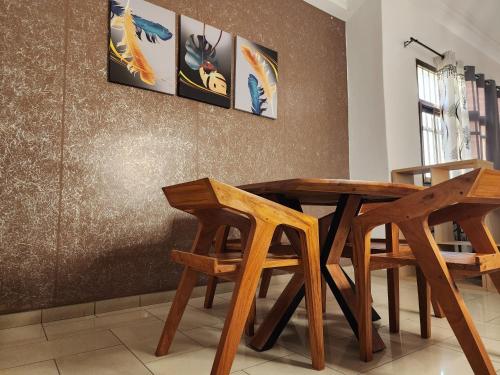 una mesa de madera y sillas en una habitación en KADIDJA APARTMENTS & SUITES Akodessewa, en Lomé