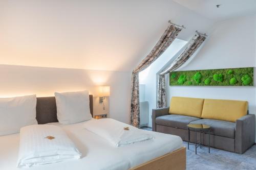 a bedroom with a large bed and a couch at Hotel Kongress in Leoben