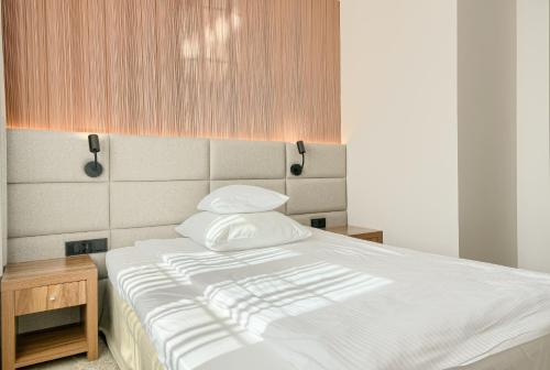 a bed with white sheets and pillows in a room at Hotel Antoni in Tomaszów Lubelski