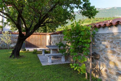 a picnic table in a yard next to a stone wall at Guest House Žerjal in Podnanos