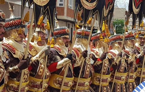 a group of men in gold uniforms in a parade at Refugio madera estilo árabe con estatuas, estanques y un pequeño zoo in Albacete