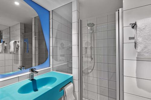 ein Badezimmer mit einem blauen Waschbecken und einer Dusche in der Unterkunft prizeotel Hamburg-St.Pauli in Hamburg