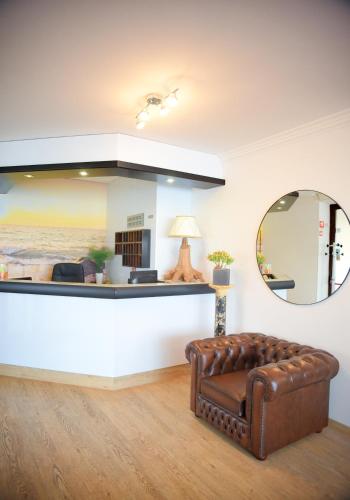 a living room with a mirror and a brown leather couch at Panorama Hotel in Muggia