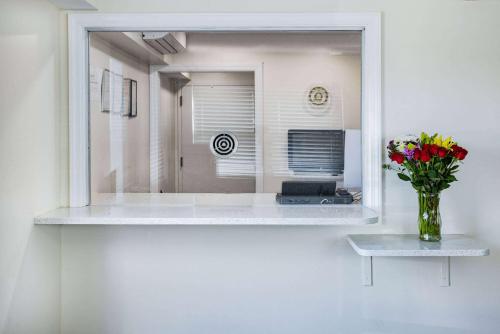a mirror with a vase of flowers on a table at Super 8 by Wyndham Lindenhurst in Lindenhurst