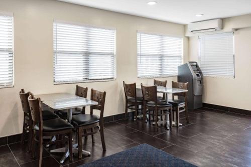 a dining room with tables and chairs and windows at Super 8 by Wyndham Lindenhurst in Lindenhurst